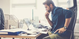 Thoughtful businessman looking at laptop in office