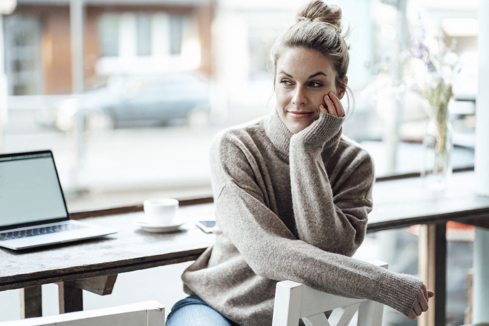thoughtful businesswoman sitting with hand on chin at cafe
