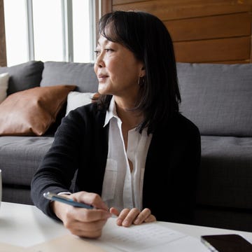 thoughtful, grateful woman writing thank you notes at home