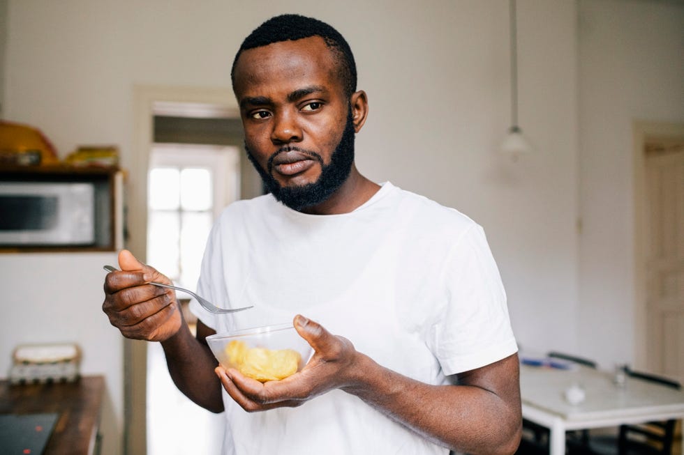 thoughtful man looking away while eating alone at home