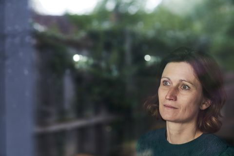 thoughtful mature woman looking through window at home