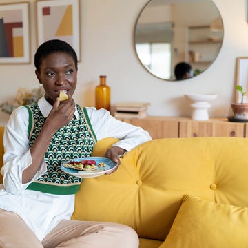 Thoughtful woman eating fruits on sofa at home thoughtful woman eating fruits on sofa at home