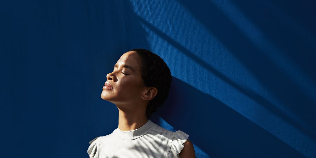 thoughtful woman standing against blue wall