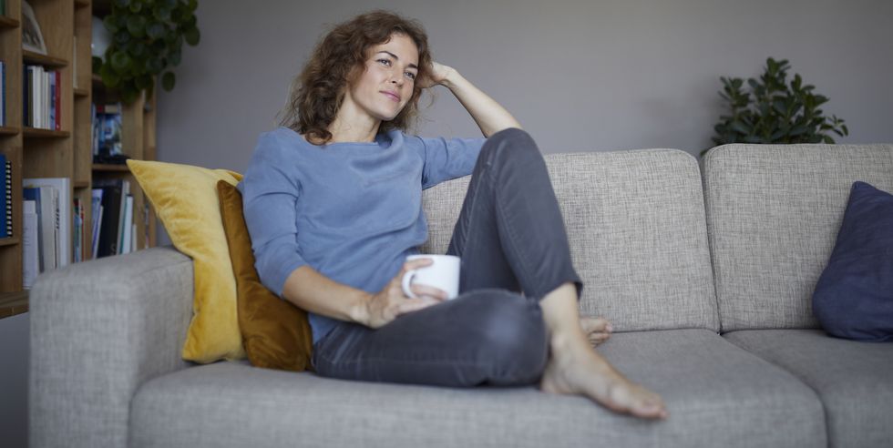 thoughtful woman with head in hands sitting on sofa at home