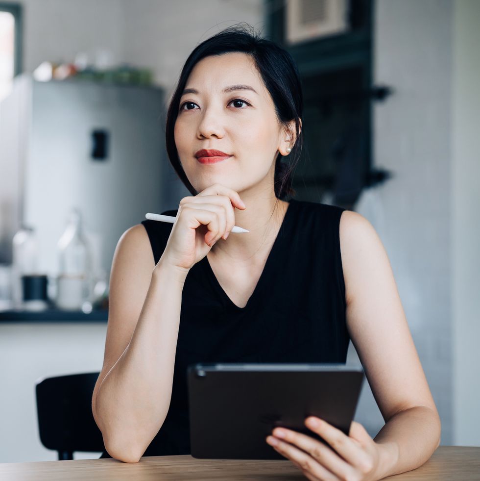 thoughtful young asian woman handling personal banking and finance with digital tablet at home planning budget and calculating expenses managing taxes and financial bills wealth management digital banking habits smart banking with technology