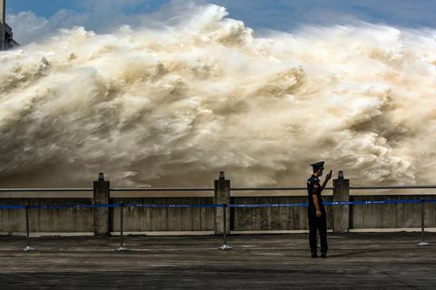 topshot   this photo taken on july 19, 2020 shows a security guard looking at his smartphone while water is released from the three gorges dam, a gigantic hydropower project on the yangtze river, to relieve flood pressure in yichang, central china's hubei province   rising waters across central and eastern china have left over 140 people dead or missing, and floods have affected almost 24 million since the start of july, according to the ministry of emergency management photo by str  afp  china out photo by strafp via getty images