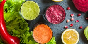 three glasses of different fresh juice beet, carrot and kiwi juices on grey background