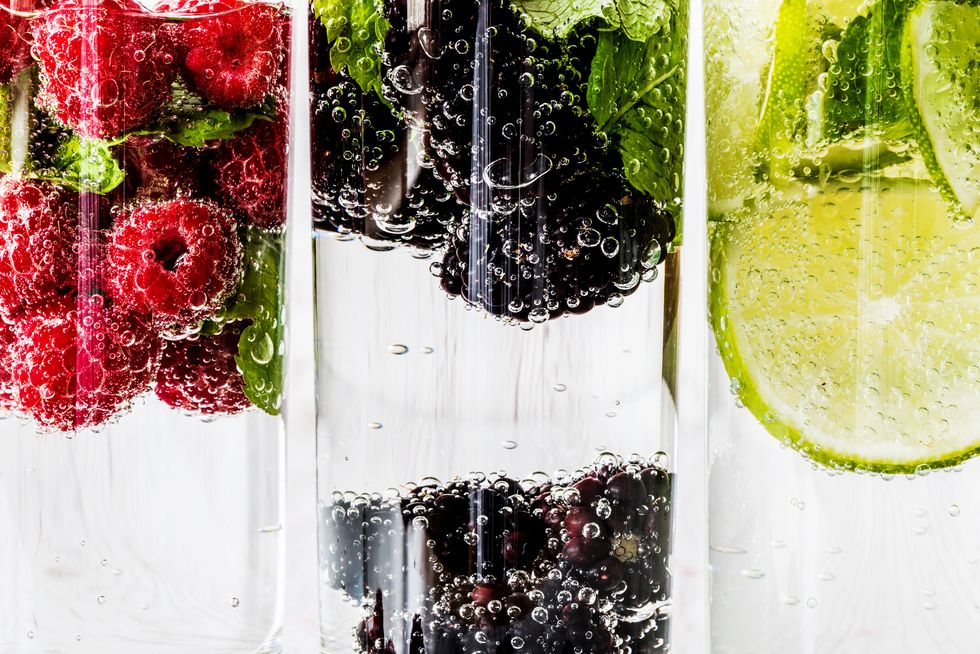 Three kinds of detox water with blackberry, strawberry, lime with ingredients on white wooden background. Super macro