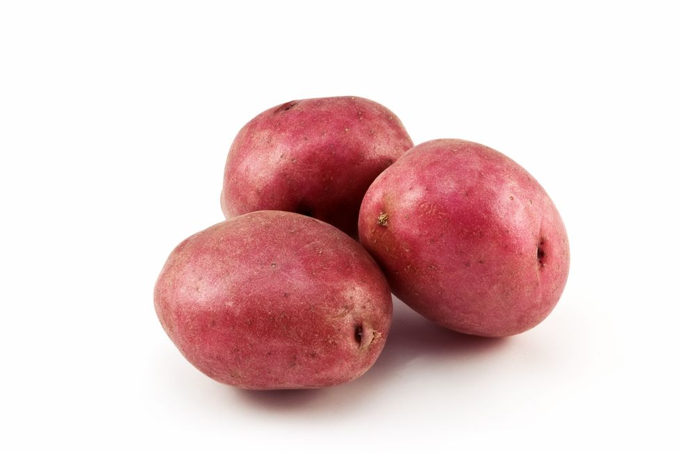 three red potatoes on a white background