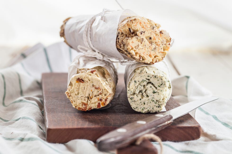 three rolls of differently flavoured compound butters on chopping board