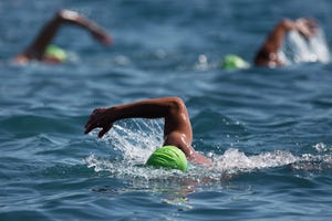 three swimmers swim in the ocean