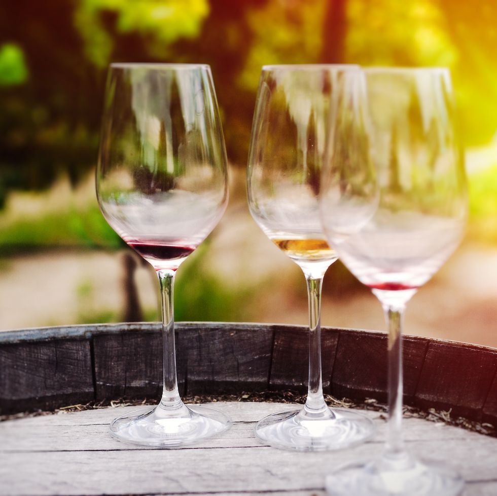 three wine glasses on barrell at vineyard in sonoma, california
