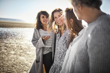 three women and mature man talking on the beach