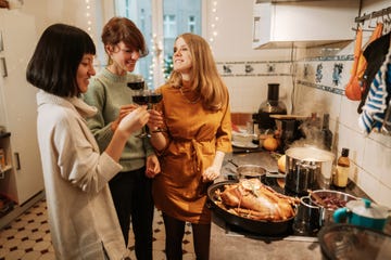 three women drinking wine while preparing christmas dinner at home
