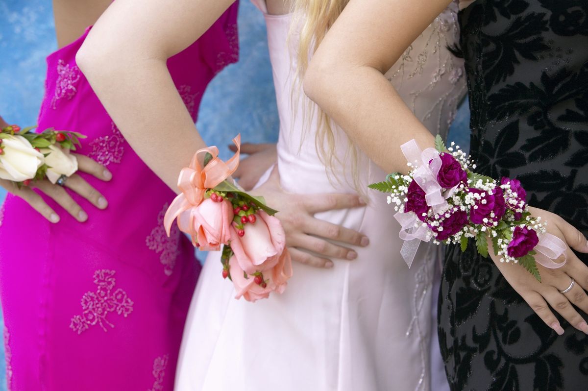three women standing dressed for a high school prom wearing corsages