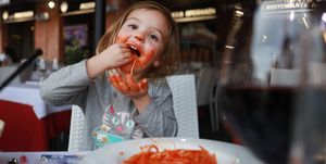 a three year old girl eating pasta, siena, tuscany, italy