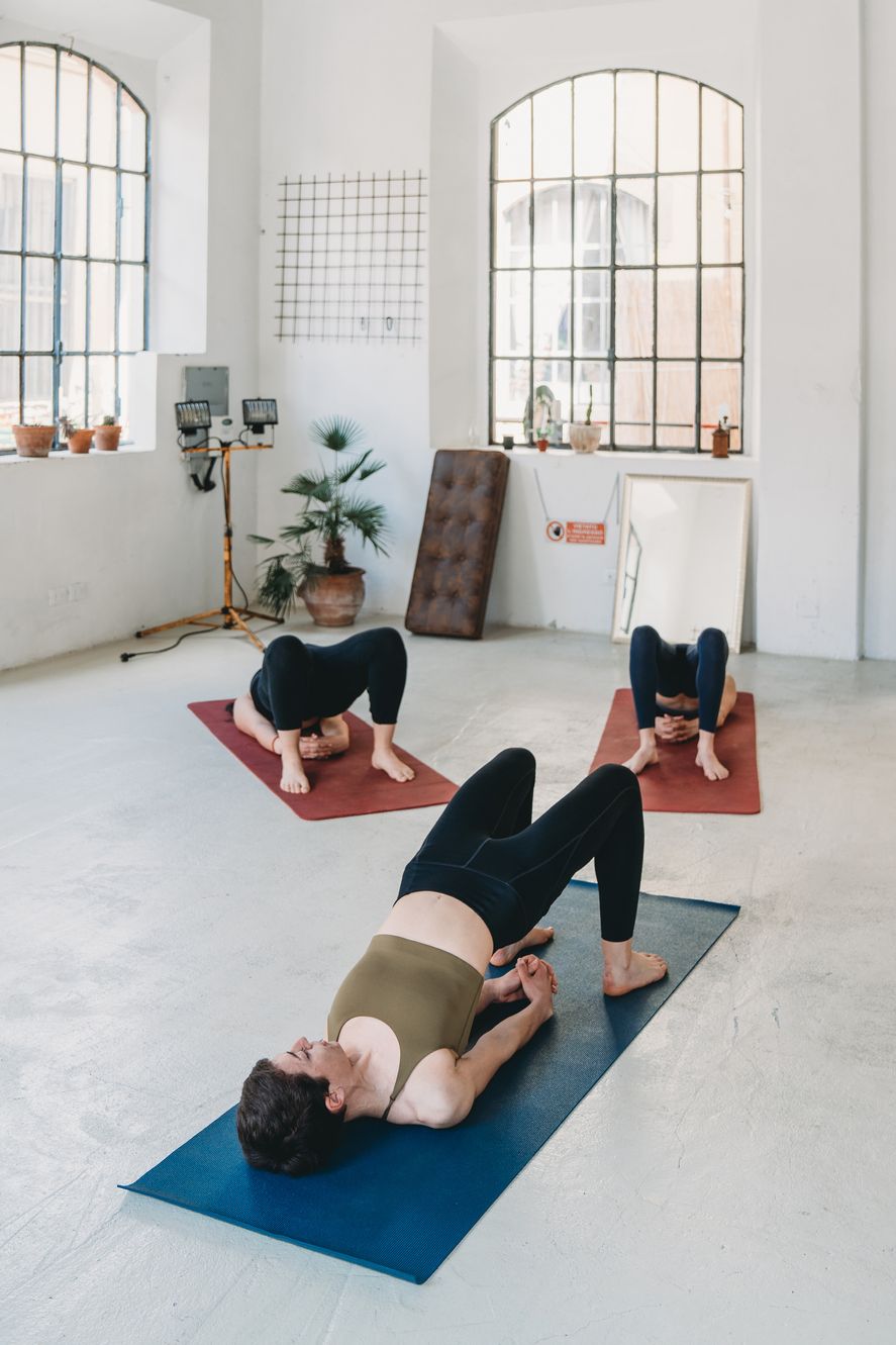 three young adult women are practicing yoga in a modern loft