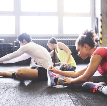 Three young people stretching in gym