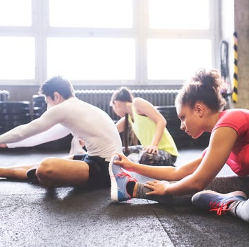 Three young people stretching in gym Three young people stretching in gym