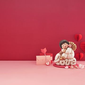 a couple of dolls sitting on a pink surface with a pink background