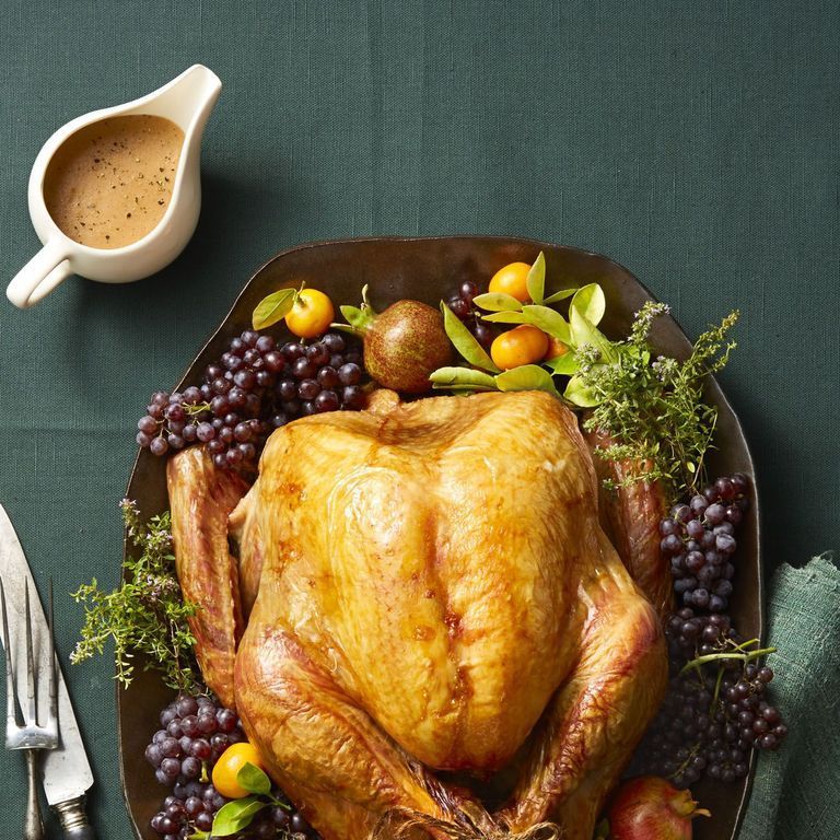 christmas foods a turkey on a platter surrounded by grapes and oranges and green sprigs