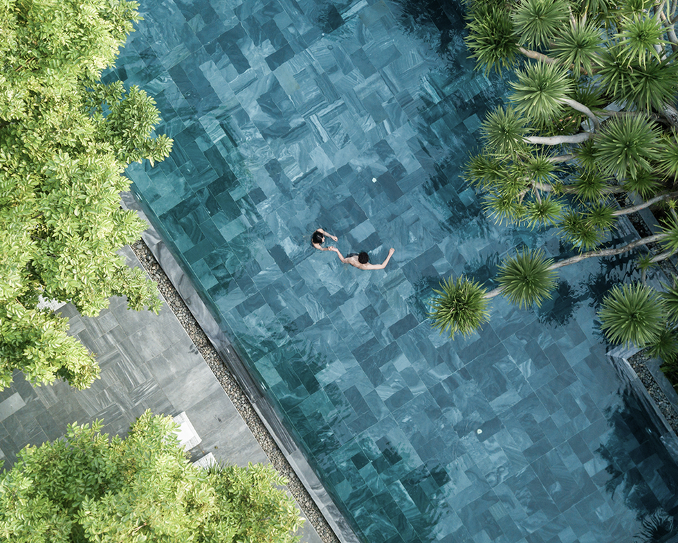 two individuals swimming in a turquoise pool surrounded by greenery two individuals swimming in a turquoise pool surrounded by greenery