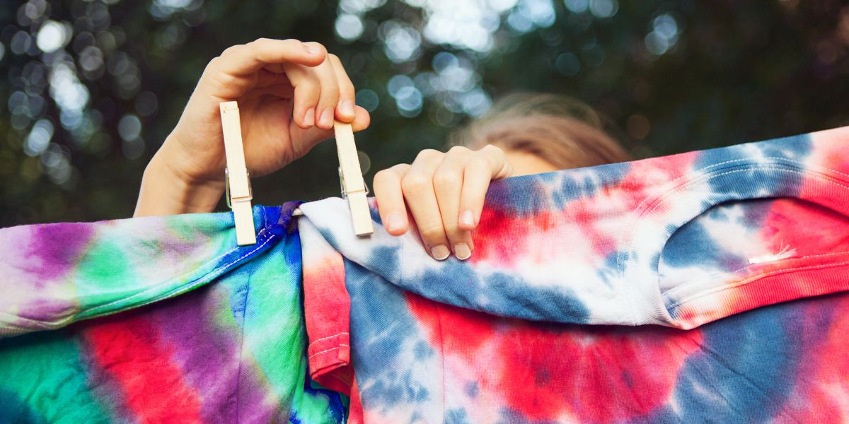 girl pinning tie dyed tshirts to clothes line