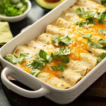 green enchiladas casserole in a baking dish topped with cheese and cilantro