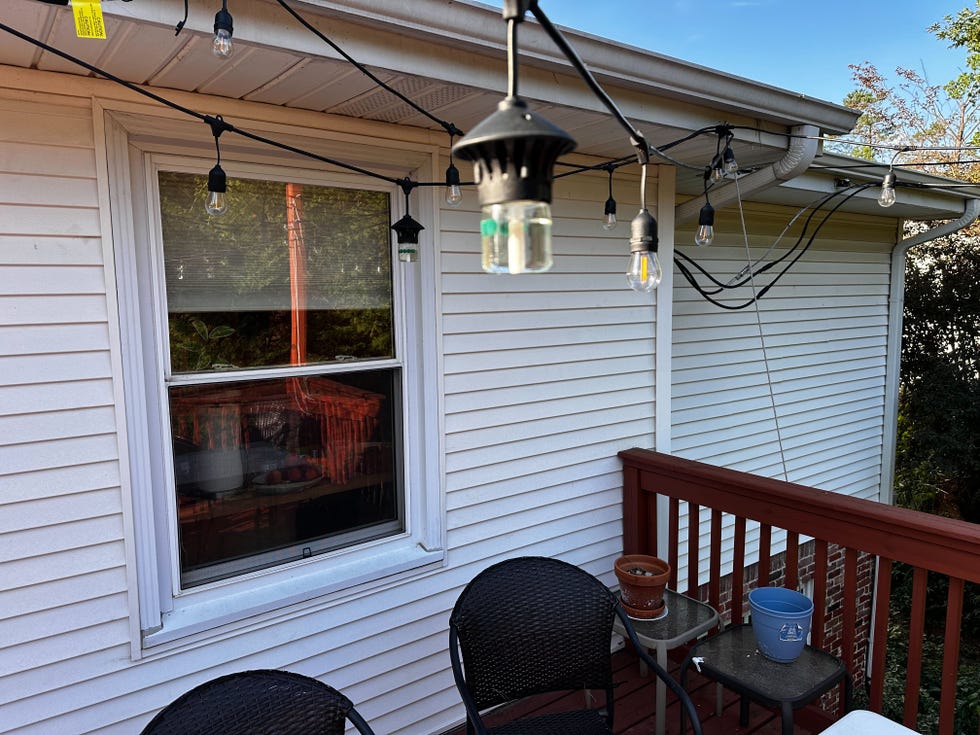 a porch with a table and chairs and string lights