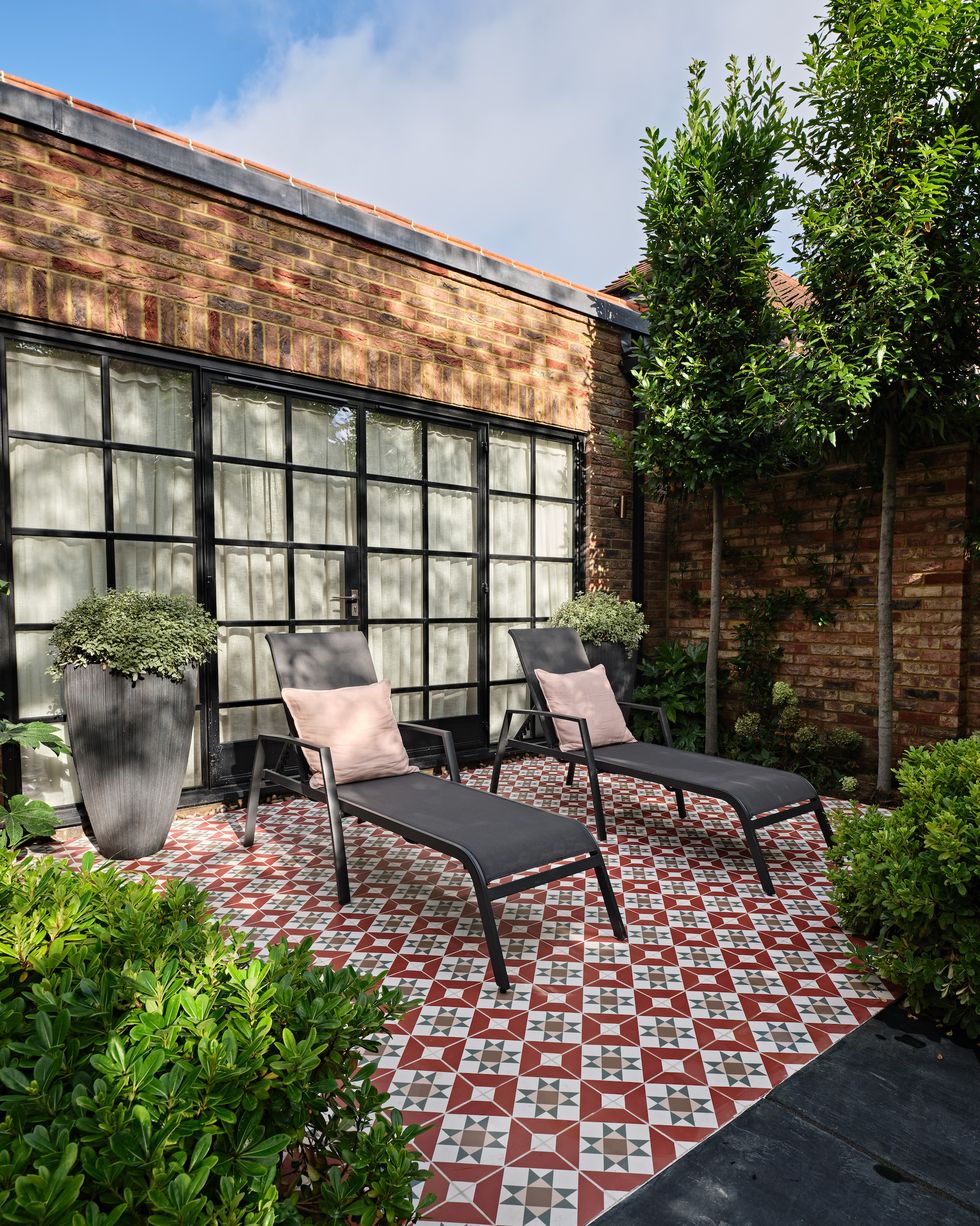 patterned tiles in an outside patio with black sun loungers on top