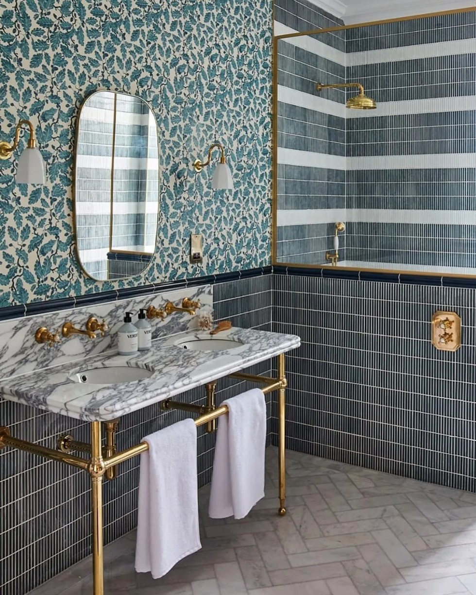 a tiled bathroom with botanical wallpaper, a sink and mirror