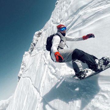 Tilt Image Of Man Snowboarding Against Clear Sky