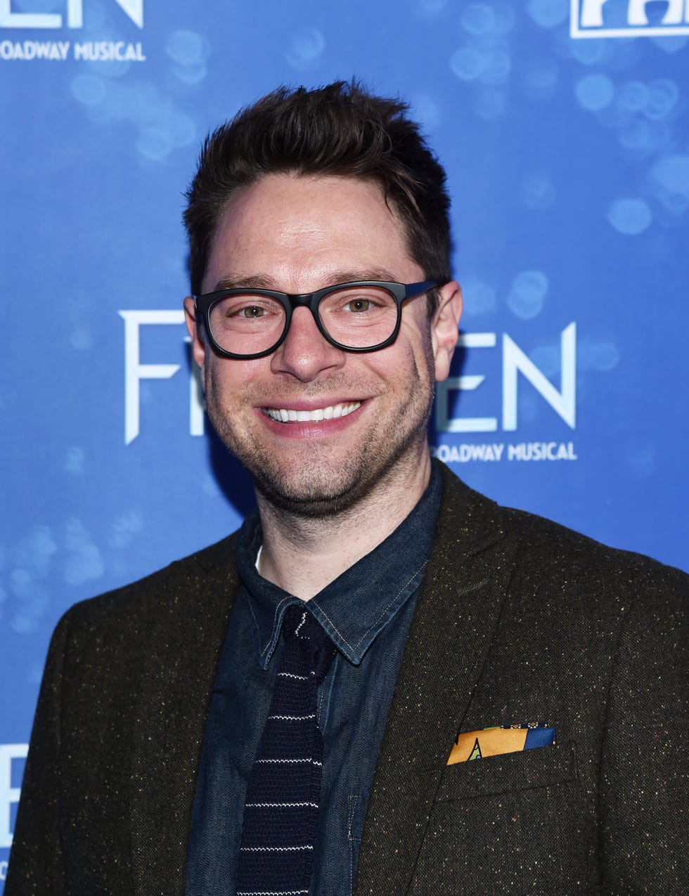 tim federle smiling and wearing glasses, a blue denim shirt, blue and white stripey tie and brown blazer jacket