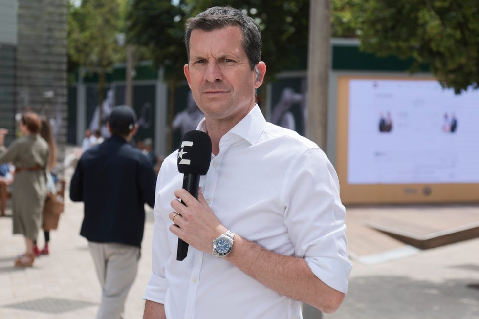 tim henman holds a microphone as he stands in a courtyard at the roland garros tennis complex