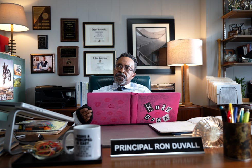 tim meadows as mr duvall holding the burn book behind a desk, mean girls