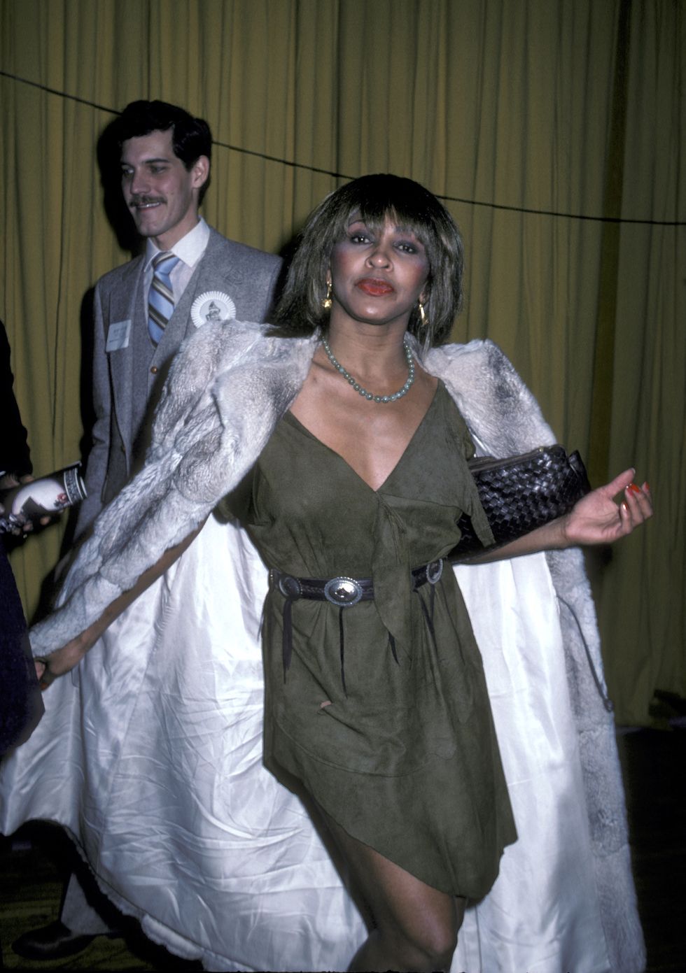 tina turner looks at the camera while standing in front of a man