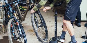 checking tire pressure on a dirty mountain bike