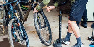 checking tire pressure on a dirty mountain bike