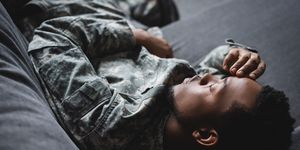 tired african american soldier in military uniform sleeping in sofa at home