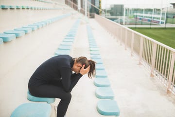 tired and powerless woman sitting on stadium seat after hard running training