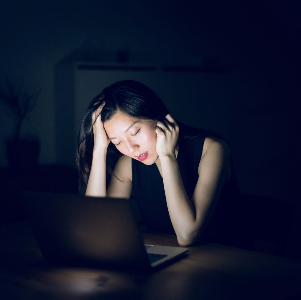 tired and sleepy woman working in front of laptop till late in office