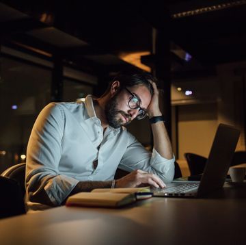 tired businessman in office at night typing on laptop