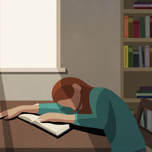 tired college student sleeping on book at sunny table in library