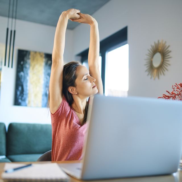 tired female freelancer stretching arms while sitting in home office