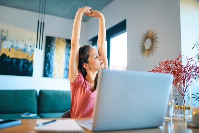 tired female freelancer stretching arms while sitting in home office