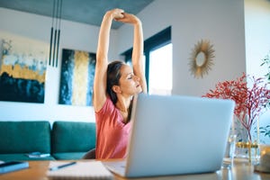 tired female freelancer stretching arms while sitting in home office