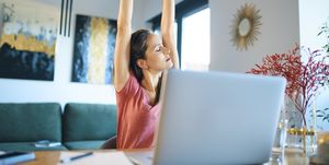 tired female freelancer stretching arms while sitting in home office