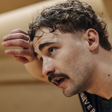 tired male athlete wiping sweat while contemplating at sports court