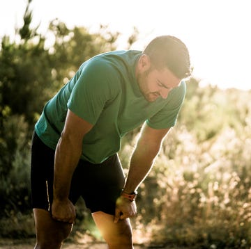 Tired male runner bending in forest tired male runner bending in forest