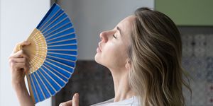 tired overheated woman using wave fan suffer from heat sweating, cools herself,  feels sluggish
